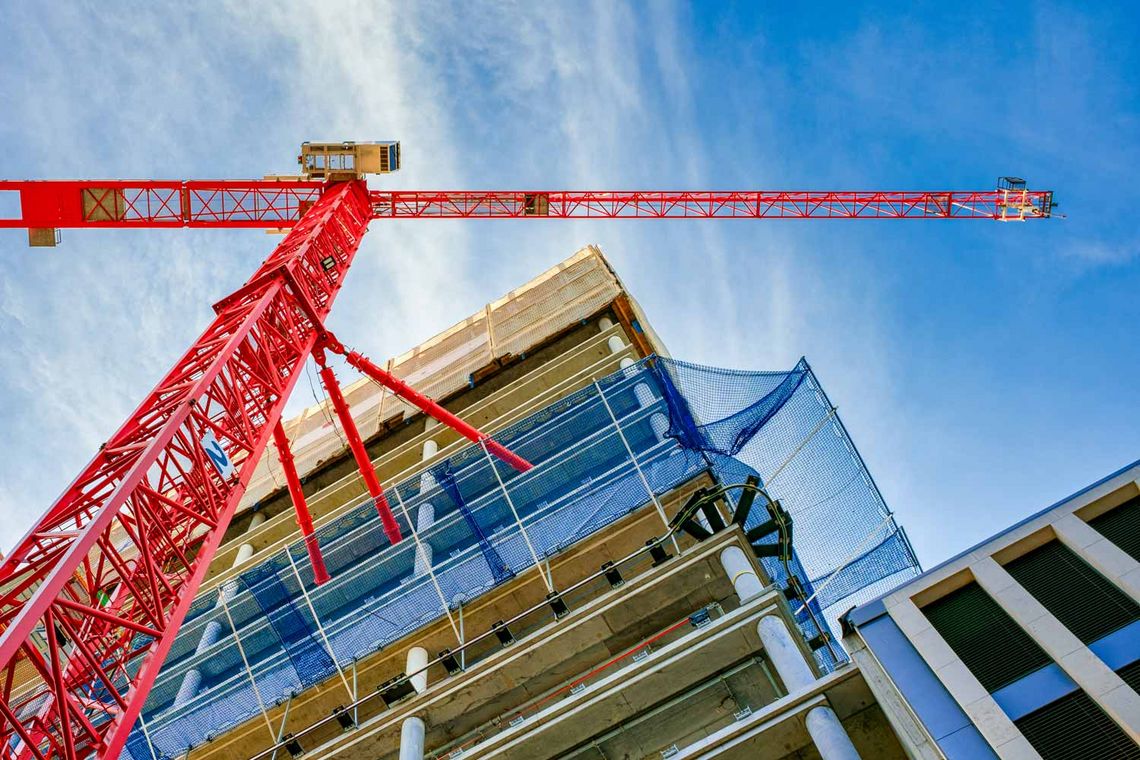 Foto einer Baustelle mit großem, roten Krahn