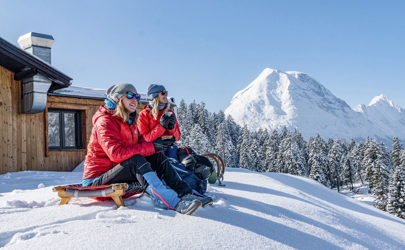 Winterlandschaft mit zwei Frauen auf Rodeln sitzend