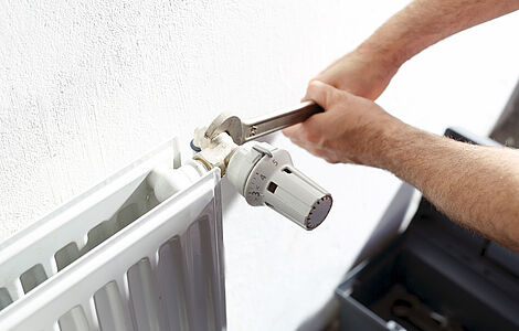 Jemand schraubt an einem Heizkörper