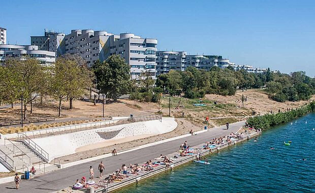 Blick von der Reichsbrücke auf einen kleinen Teil der Neuen Donau im Vordergrund und einem Wohnbau im Hintergrund