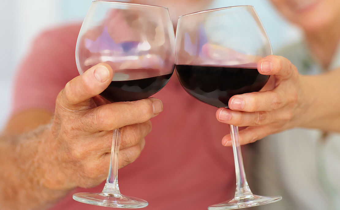 Mann und Frau stoßen mit einem Glas Rotwein an