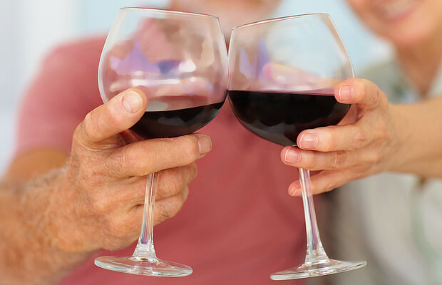 Mann und Frau stoßen mit einem Glas Rotwein an