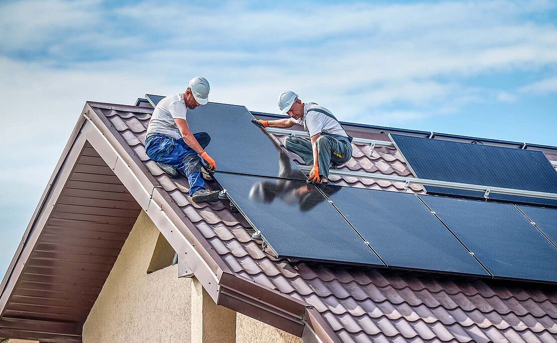Arbeiter, die Solarpaneele am Dach montieren