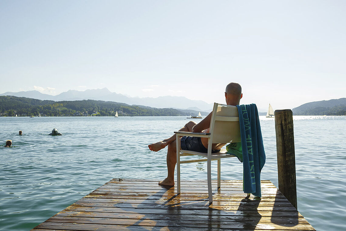 Mann in Badehose im Liegestuhl auf Steg am Wörthersee