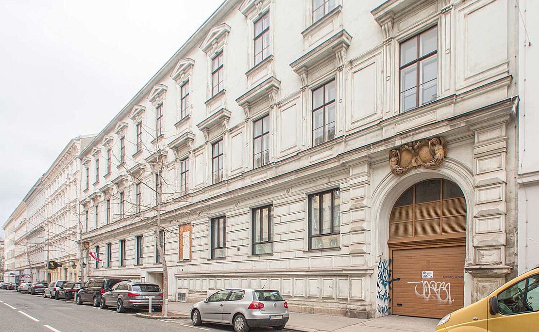 Blick auf mehrere Gebäude in Wien, davor eine Straße und Autos