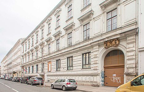 Blick auf mehrere Gebäude in Wien, davor eine Straße und Autos