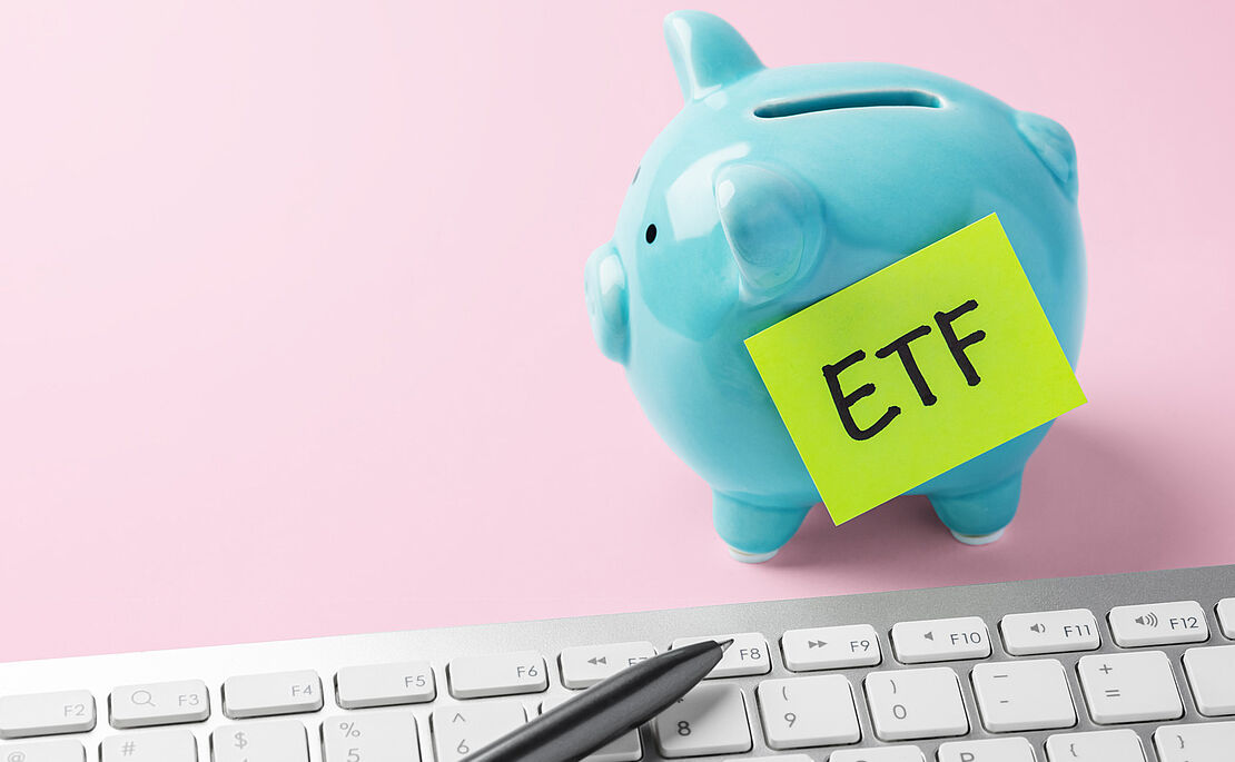 Blaues Sparschwein auf rosa Untergrund mit einem gelben Post-It beklebt, worauf "ETF" steht