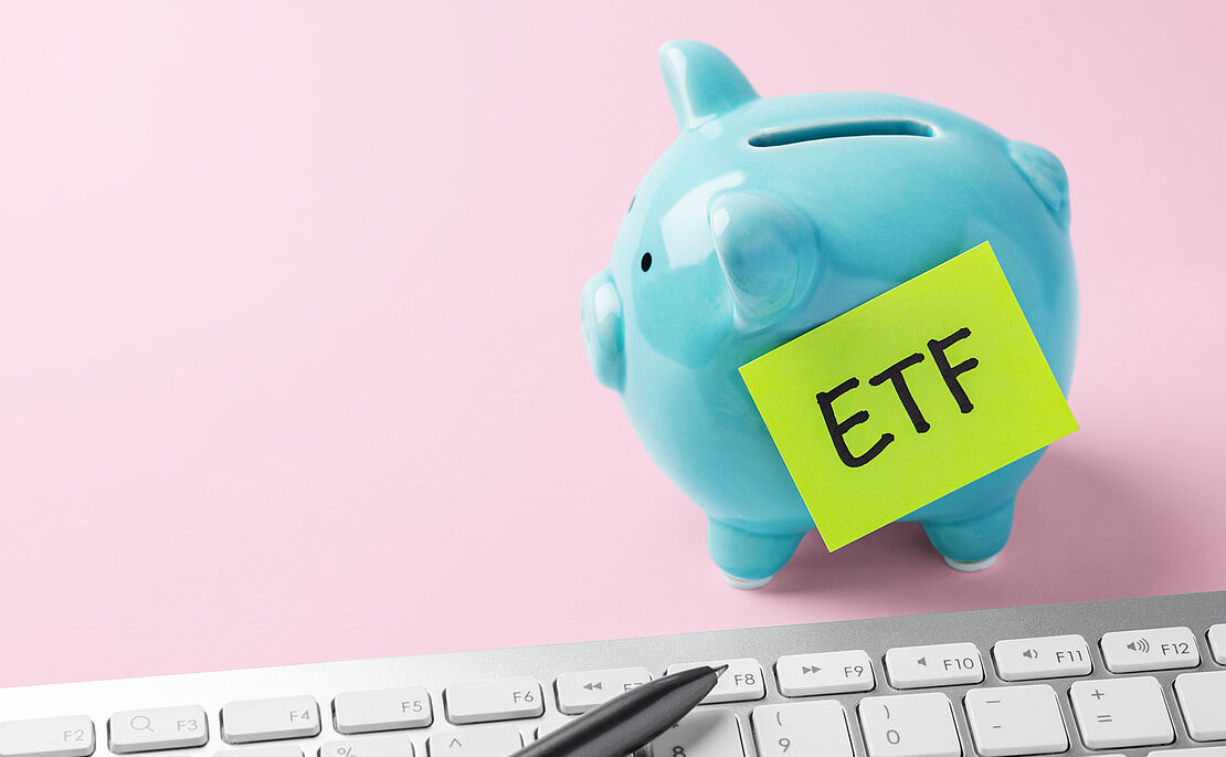 Blaues Sparschwein auf rosa Untergrund mit einem gelben Post-It beklebt, worauf "ETF" steht