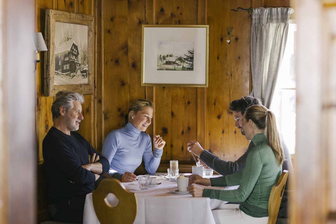 Zwei Frauen und zwei Männer an einem Tisch sitzend in einer Skihütte