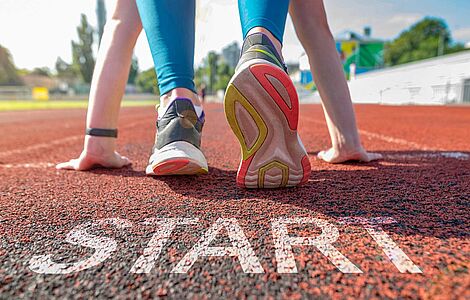 Sportler in Startposition auf einer Leichathletikbahn