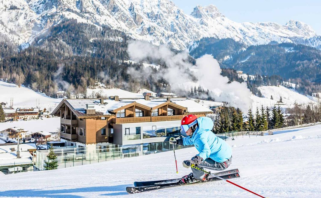 Skipiste mit Skifahrer, im Hintergrund Hotel Riederalm