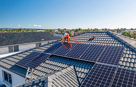 Mann am Dach, der Photovoltaikanlage montiert