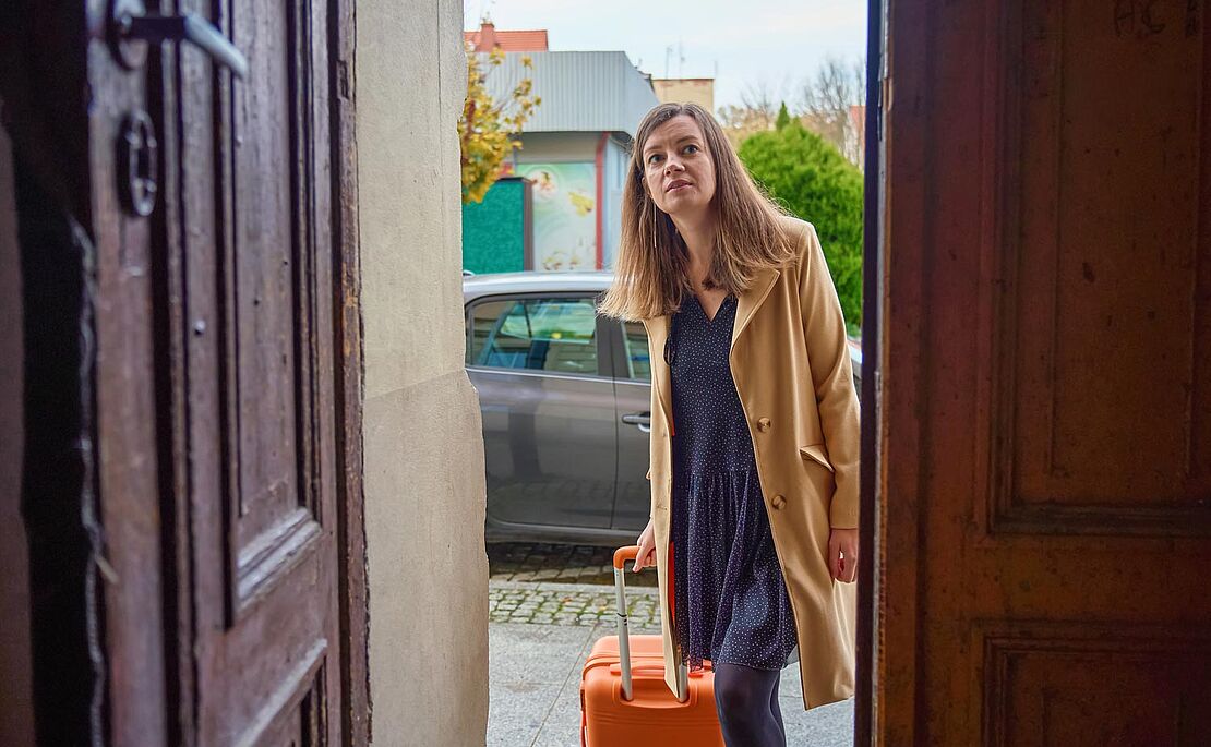 Frau mit Koffer an der Eingangstür