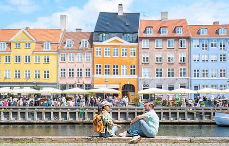 Zwei Menschen sitzen am Hafen in Dänemark