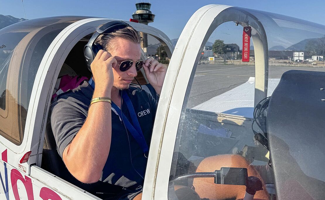 Pilot in einem Cockpit eines Kleinflugzeuges, der sich gerade eine Sonnenbrille aufsetzt