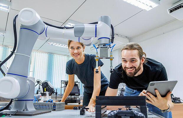 Eine Frau und ein Mann bei der Arbeit mit einem Roboter