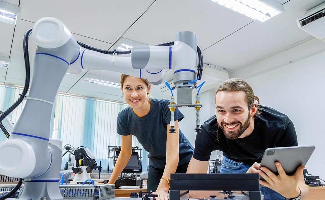 Eine Frau und ein Mann bei der Arbeit mit einem Roboter