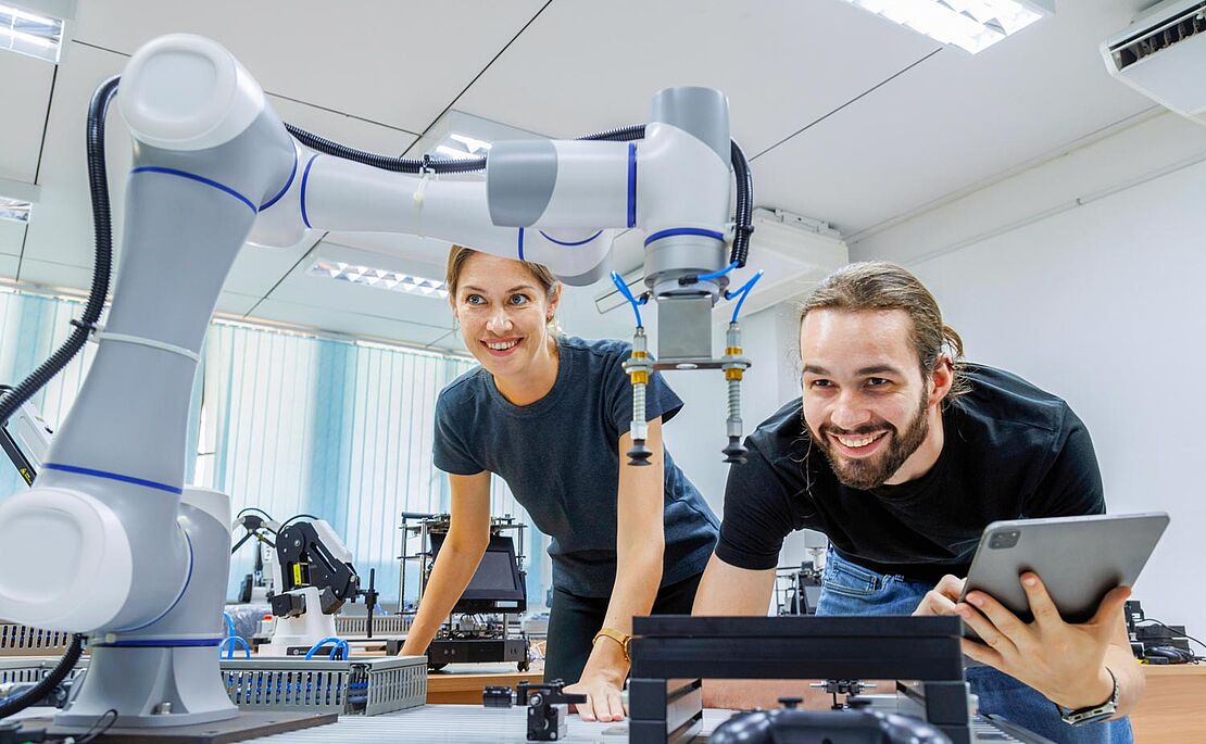 Eine Frau und ein Mann bei der Arbeit mit einem Roboter