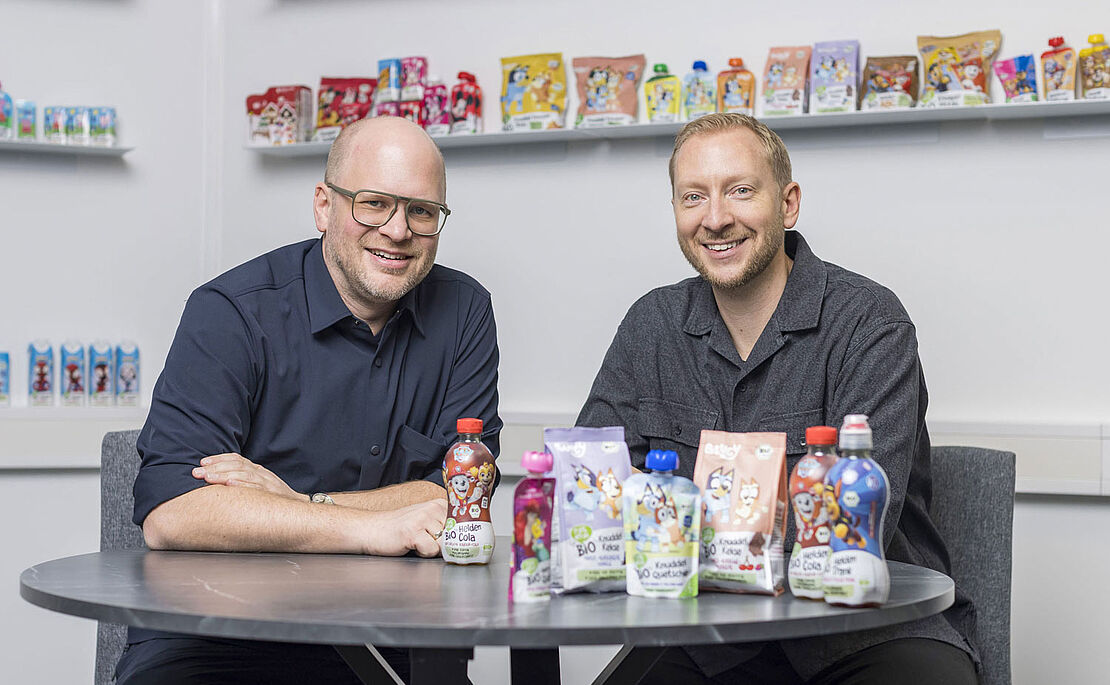 Christian Eibl und Reinhold Hinterplattner bei Tisch sitzend, vor ihnen einige ihrer Produkte