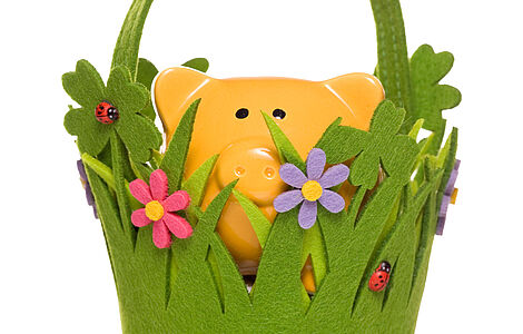 Gelbes Sparschwein in einem Filzkörbchen, das wie eine Wiese aussieht