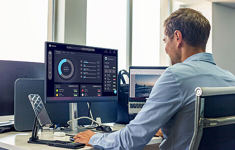 Mann von seitlich hinten, der vor seinem PC sitzt