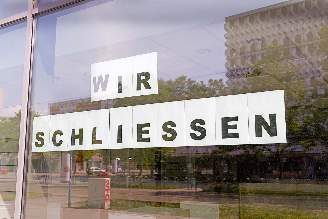 Schild mit Aufschrift Wir Schließen an Fensterfront geklebt