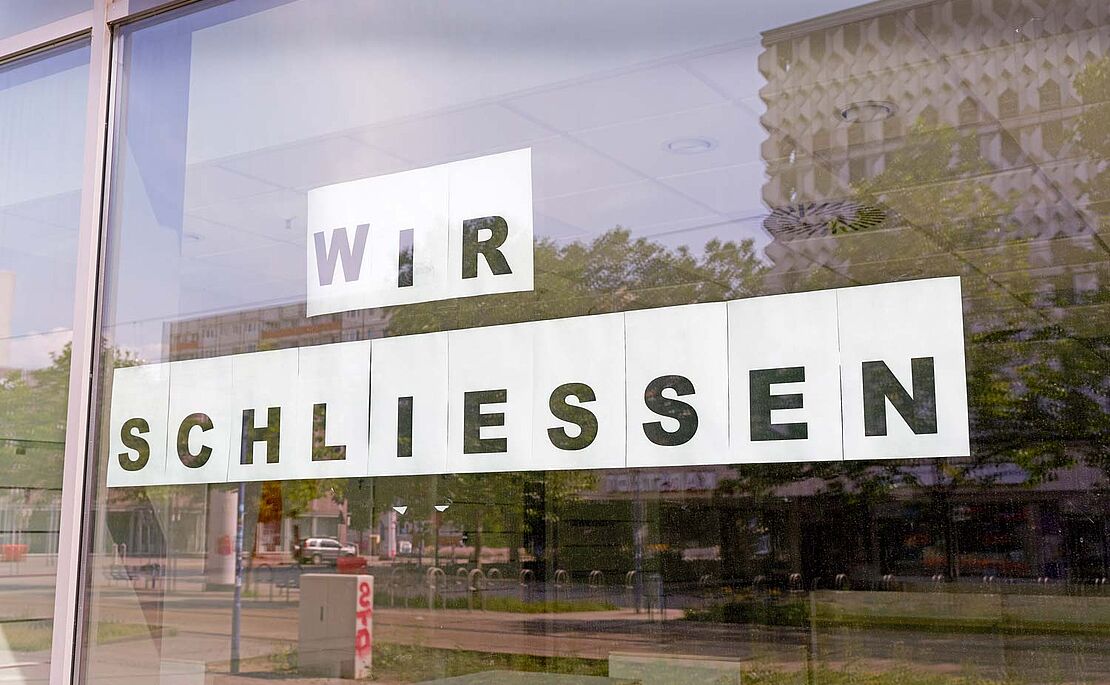 Schild mit Aufschrift Wir Schließen an Fensterfront geklebt