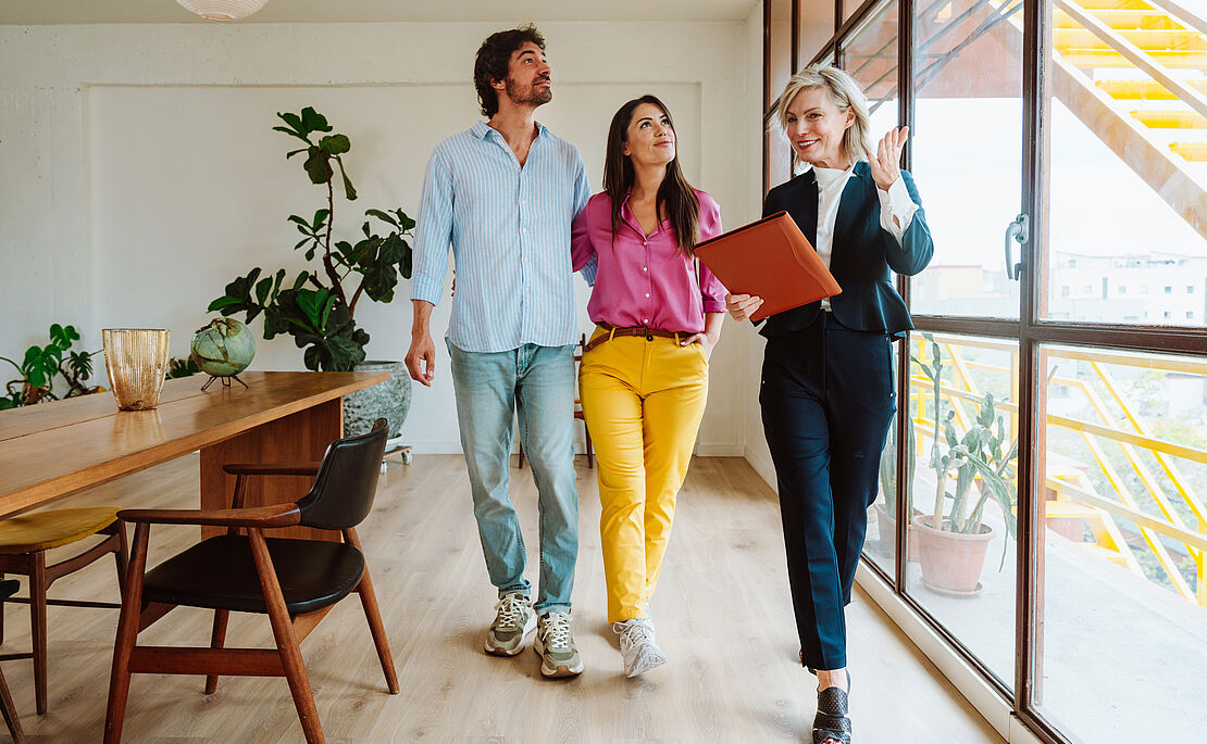 Junges Paar mit Maklerin bei einer Wohnungsbesichtigung