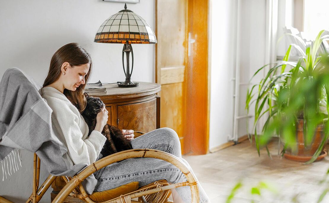 Frau kuschelt auf Sofasessel mit Hund